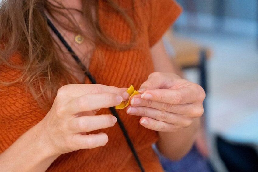 A person wearing an orange sweater holding a small yellow object. 2