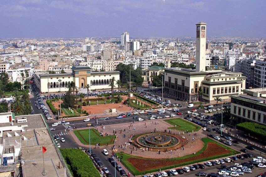 A cityscape with a central roundabout, a prominent tower, and surrounding buildings. 5