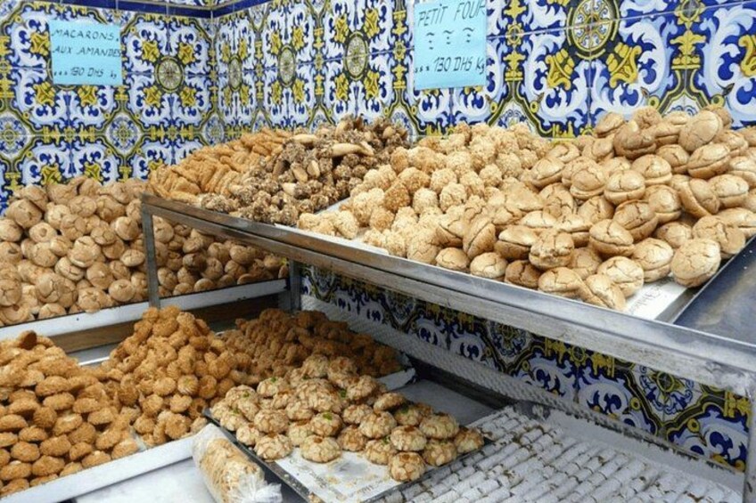 A display of various nuts and dried fruits in a market stall with blue and yellow patterned tiles in the background. 3