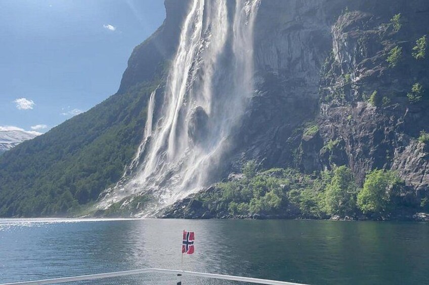 A large waterfall cascading down a steep cliff into a calm body of water. 1