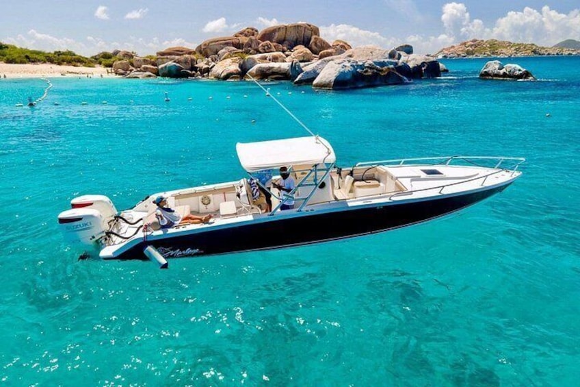 Een boot op helder turquoise water met rotsformaties op de achtergrond. 2