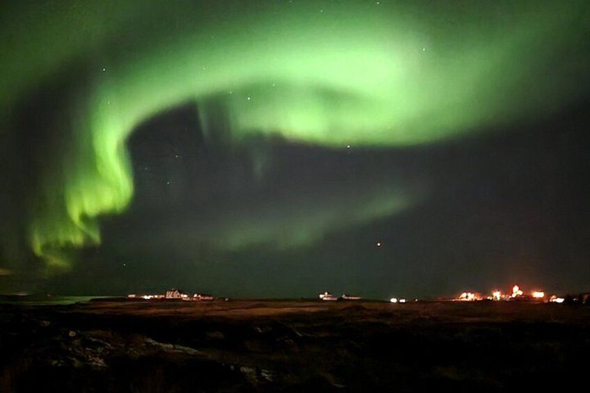 The Northern Lights over a landscape with distant lights. 4