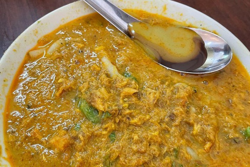 A bowl of curry with a spoon. 5