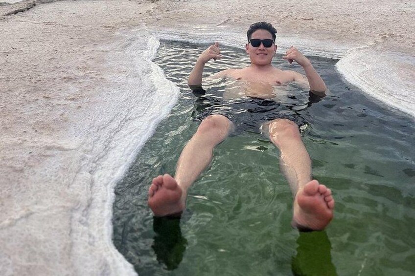 A person relaxing in a natural pool with clear water and rocky edges. 5