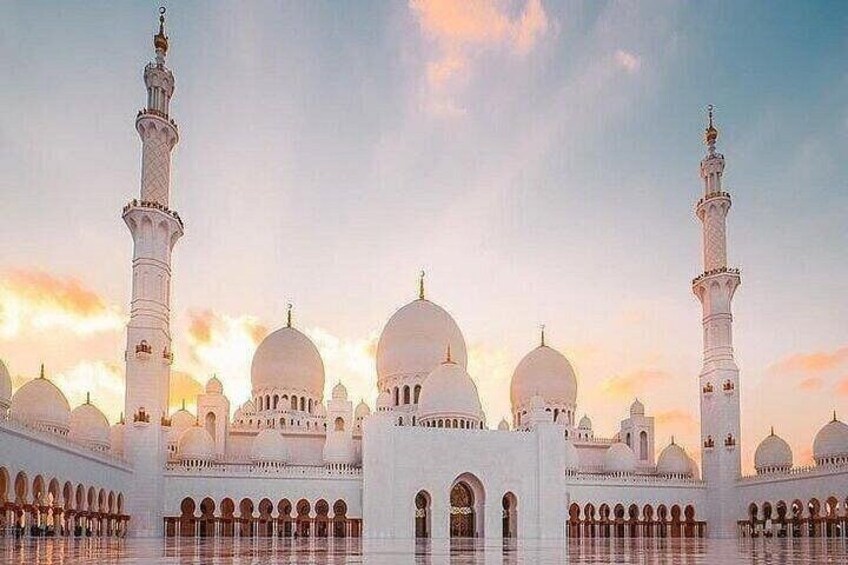 Eine Moschee mit mehreren Kuppeln und Minaretten, die sich im Wasser spiegeln. 4