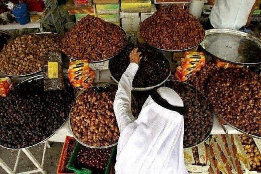 A person selecting dried fruits from large containers at a market. 2