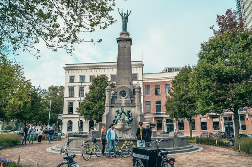 A public square with a central monument, surrounded by trees and buildings. 2