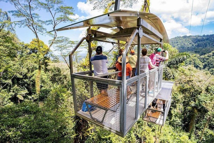 Eine Seilbahn mit Fahrgästen, umgeben von üppiger Vegetation und einer Berglandschaft. 5