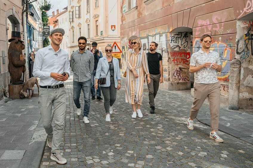 En grupp människor promenerar på en kullerstensgata med klotter på väggarna. 2