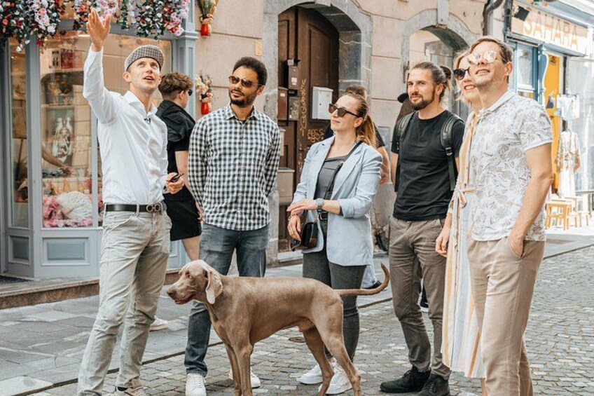 En grupp människor som står på en kullerstensgata, med en hund i mitten. 5