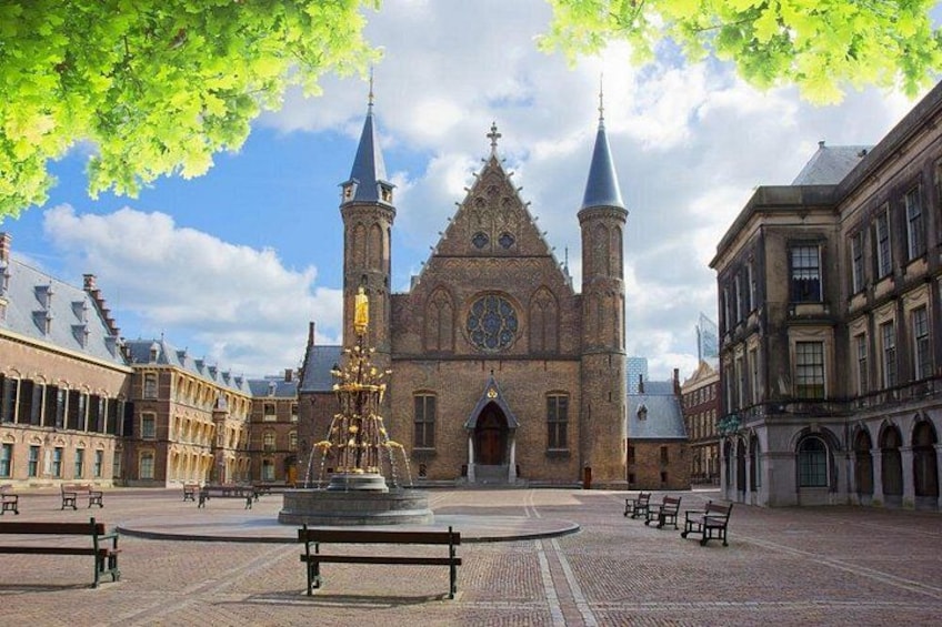 A historic church with two towers, a fountain, and benches in a square. 5