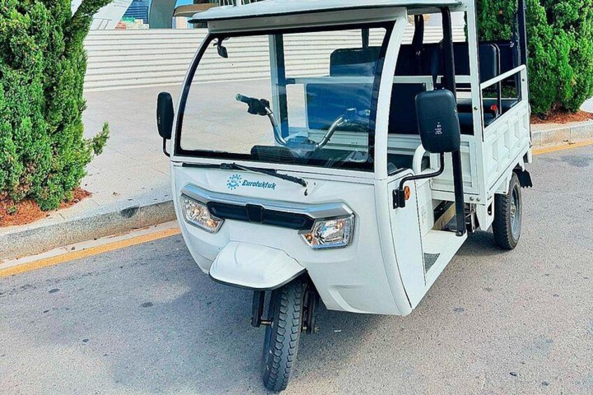A white golf cart parked on a paved surface with a building and greenery in the background. 4