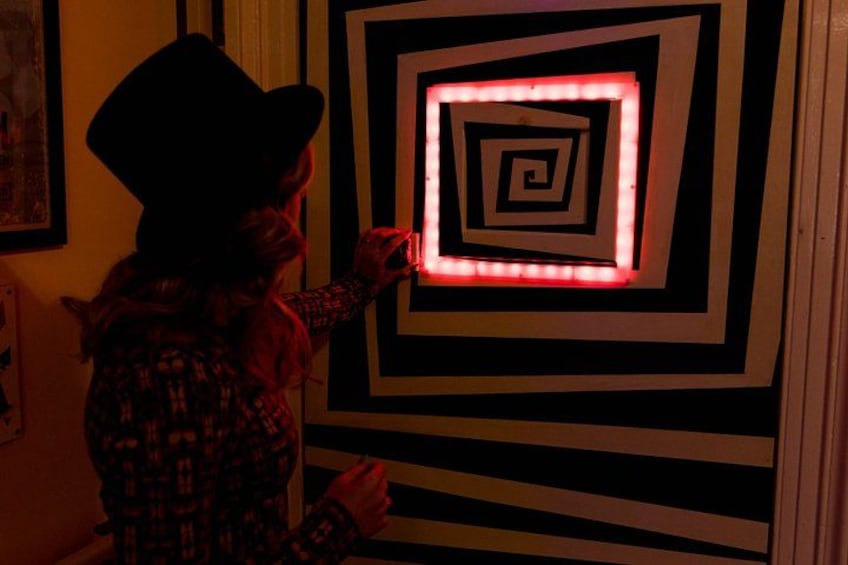 Een persoon die een wandkunstinstallatie bedient met concentrische vierkanten en rode lampen. 1