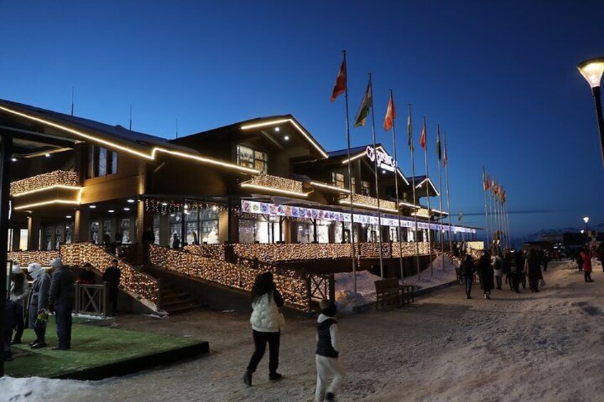 A building with multiple flags, a snow-covered ground, and people walking. 5