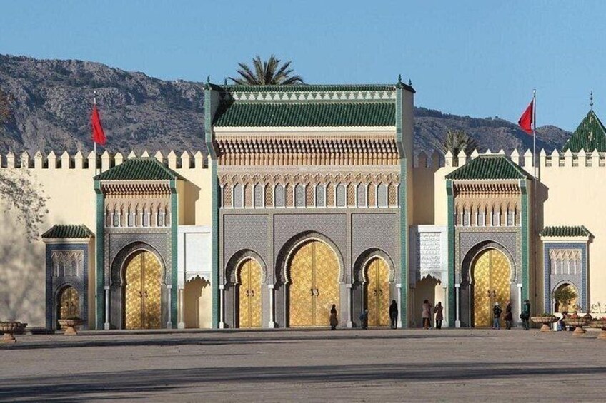 Una gran y ornamentada puerta con múltiples arcos y diseños intrincados, con montañas al fondo. 3