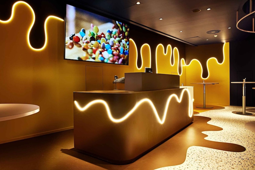 A modern reception area with a large TV screen, a reception desk, and a unique wavy light design on the walls and floor. 5