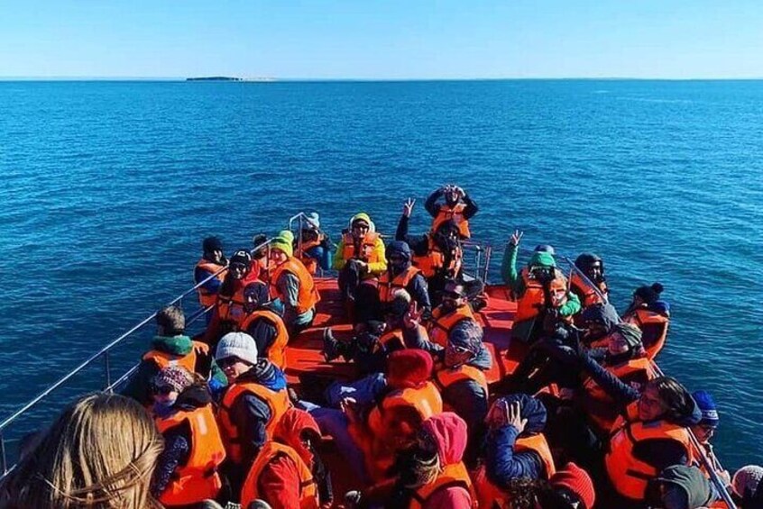 A group of people on a boat wearing orange life jackets. 2