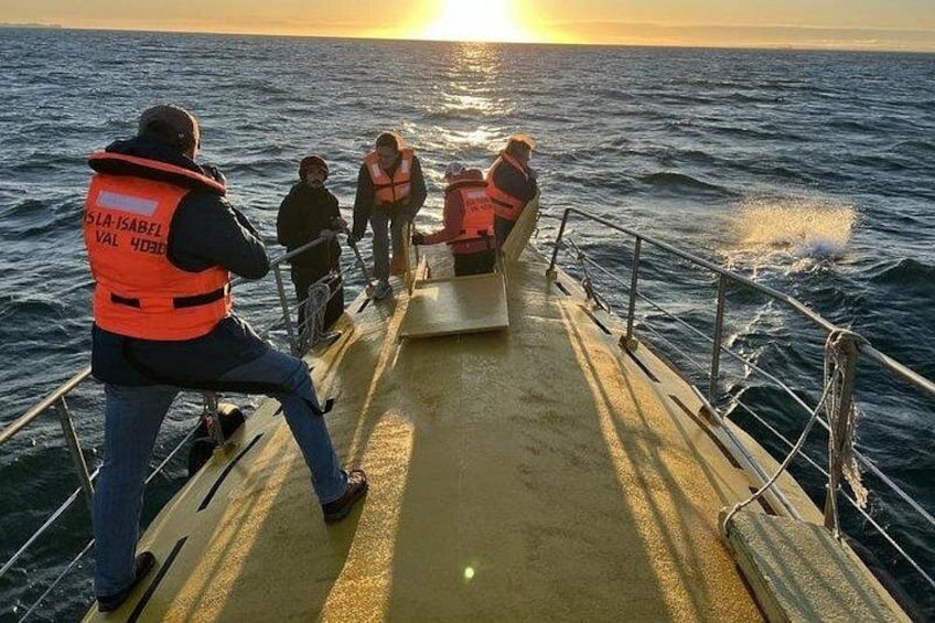 A boat with people wearing life jackets, a sunset in the background, and a calm sea. 5