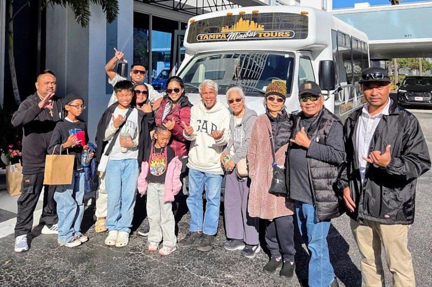 En grupp människor poserar framför en turistbuss med texten ”Tampa Sunshine Tours” på. 5