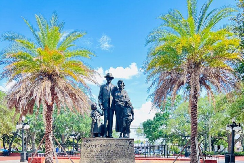 A statue of two figures with a plaque reading 'Immigrant Statue'. 4