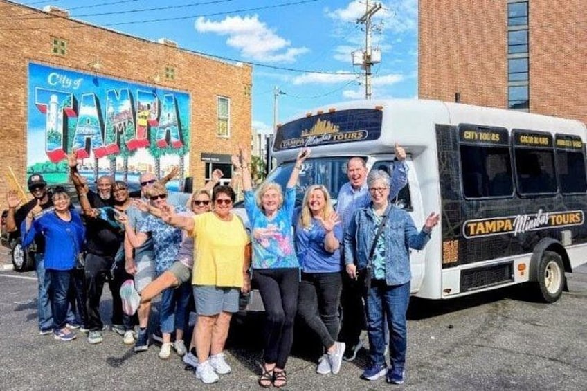 A group of people posing in front of a bus with 'City of Tampa' and 'Tampa City Tours' written on it. 1