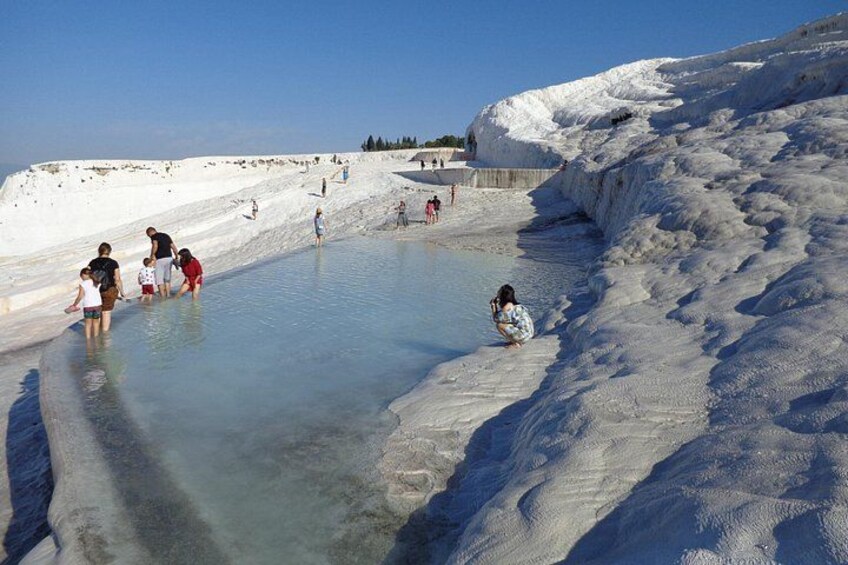Un grupo de personas cerca de una piscina natural con depósitos minerales. 4