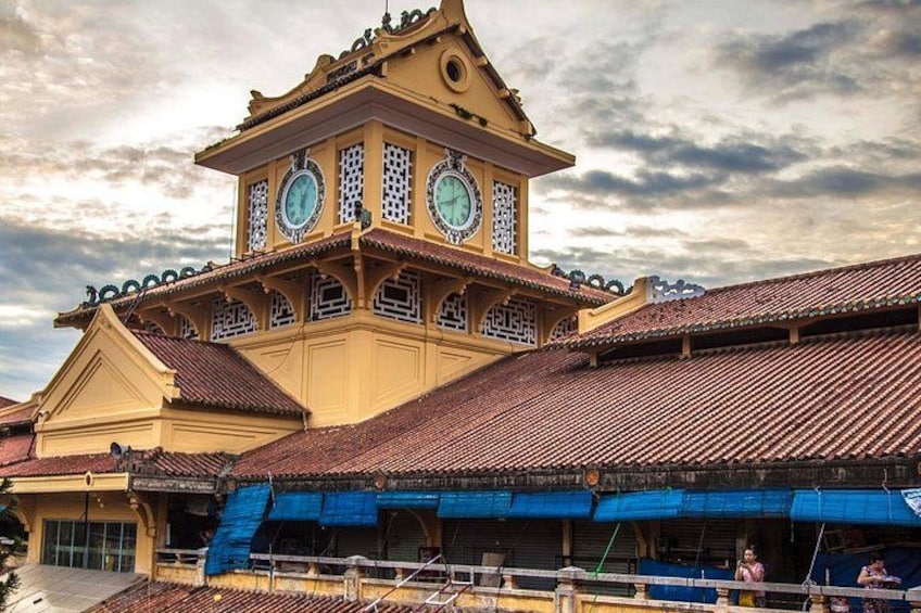 Un edificio tradicional con una torre de reloj, un toldo azul y un tejado de tejas. 2