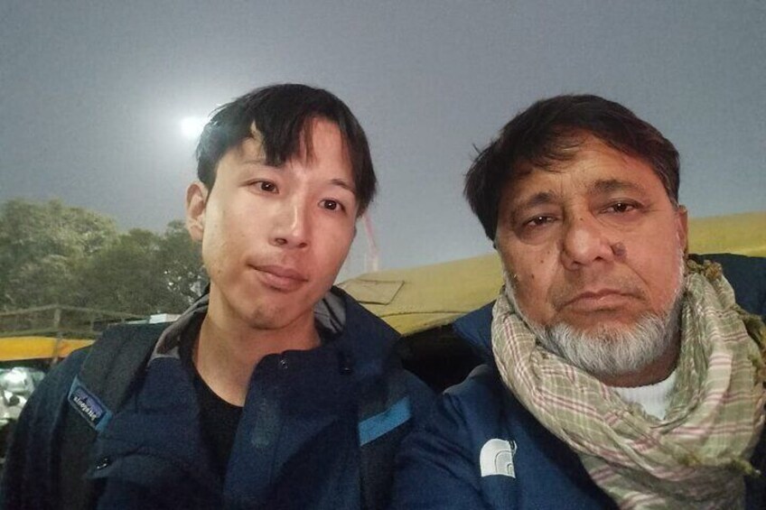 Two people sitting outdoors at night with a vehicle in the background. 2