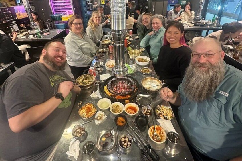 A group of people dining at a restaurant with a variety of dishes and a grill. 3