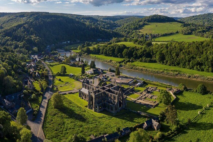 A historic castle surrounded by lush green fields and a river. 5