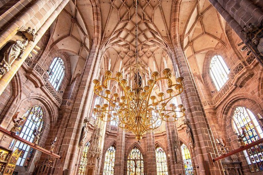 A cathedral interior with a large golden chandelier, arched windows, and Gothic architecture. 5