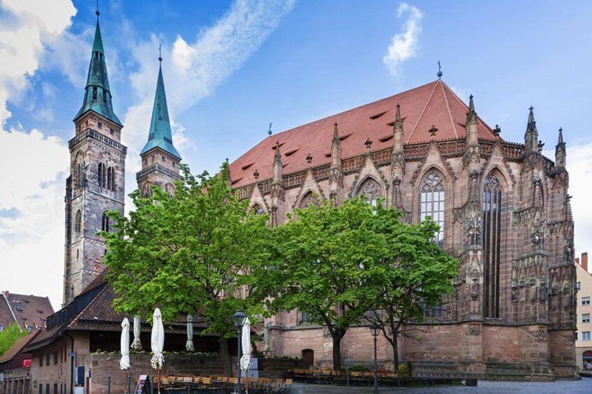 A historic church with two towers and a large tree in front. 3