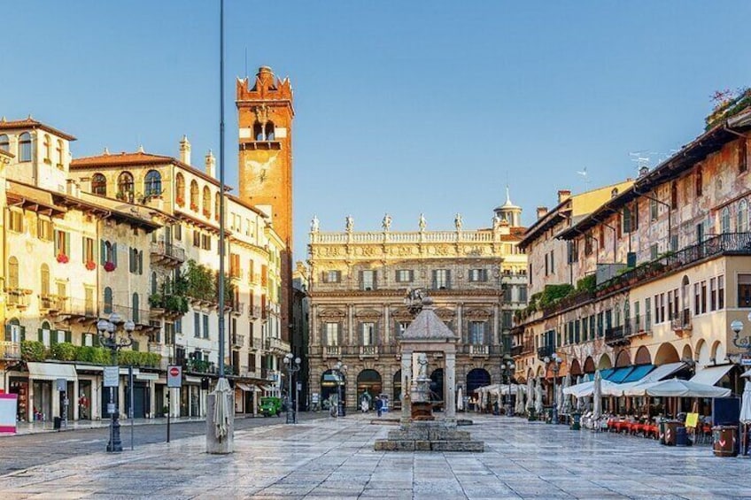 A historic square with a prominent tower, ornate buildings, and a fountain. 1