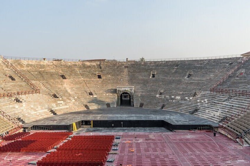 An empty amphitheater with tiered seating and a central stage. 4