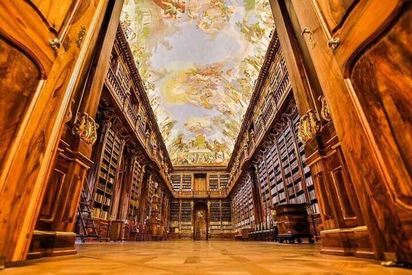 Una biblioteca imponente con estanterías de madera decoradas y un techo con frescos detallados. 3