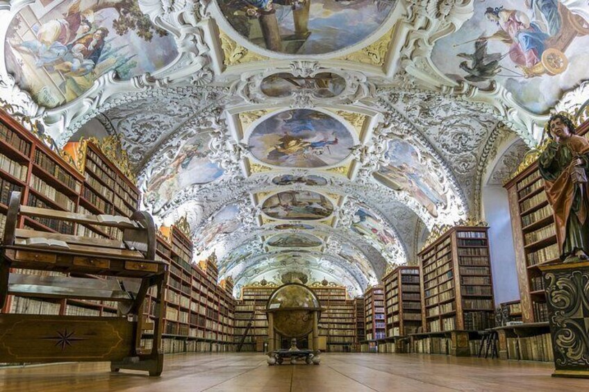 Interior de una biblioteca ornamentada con techos altos, frescos detallados y extensas colecciones de libros. 2