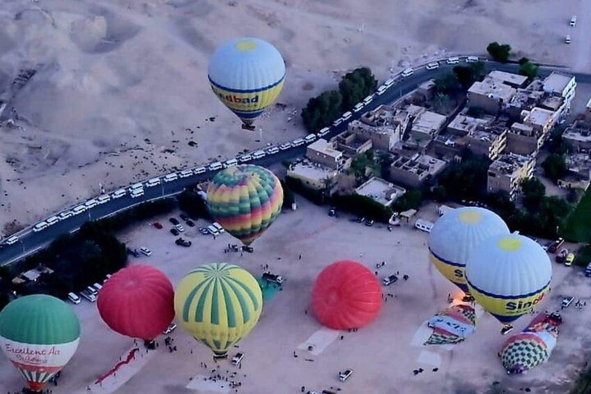 A desert landscape with a road, hot air balloons, and a small settlement. 4