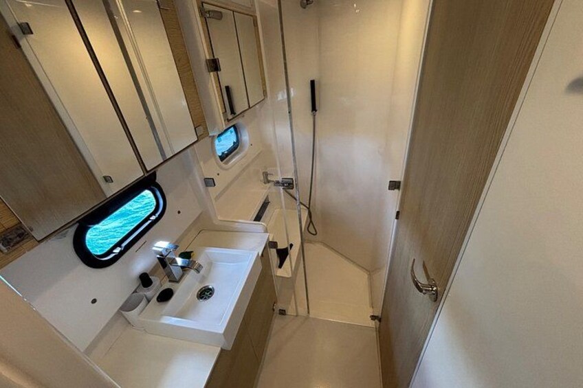 A compact bathroom with a sink, mirror, and shower. 2