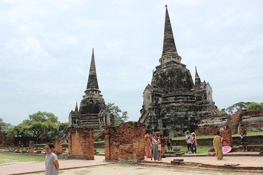Ancient temple ruins with two prominent spires, surrounded by visitors. 3