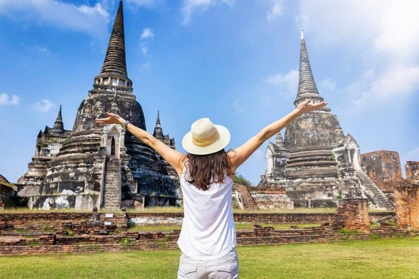 A person with arms raised in front of ancient temple ruins. 1