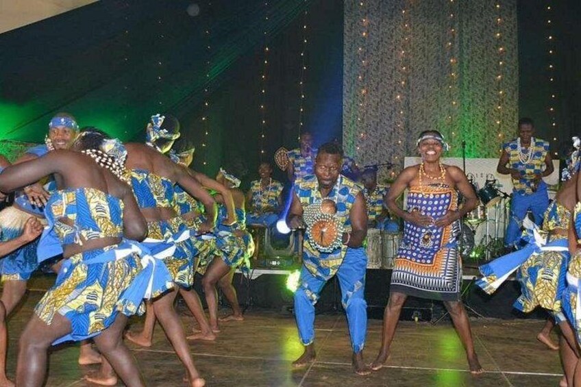 A group of people performing a dance on a stage with a patterned backdrop. 3