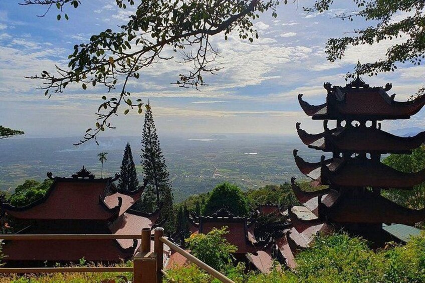 A pagoda, a traditional multi-tiered roof structure, overlooking a scenic landscape with a view of distant hills and a clear sky. 3