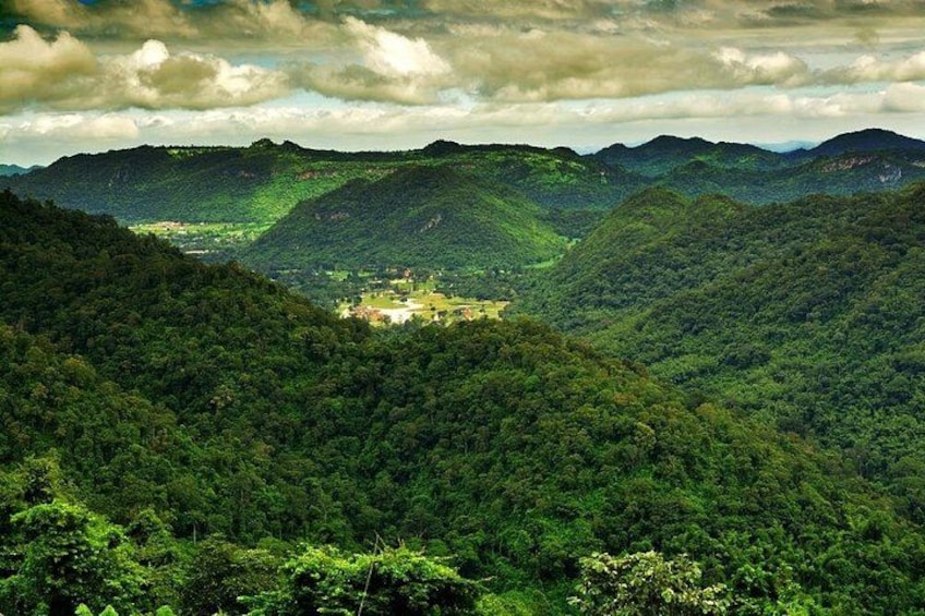 A valley with a small settlement surrounded by dense forest and hills. 5