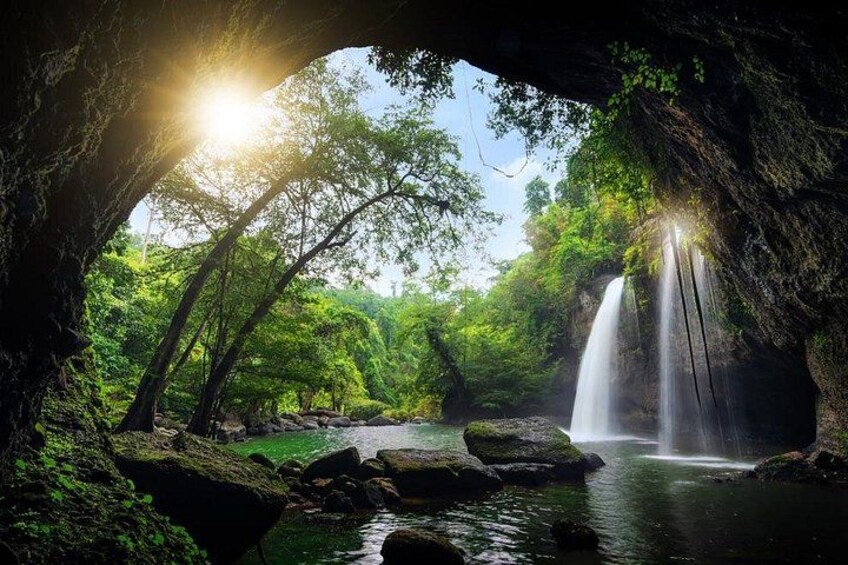 A waterfall in a forested area with sunlight filtering through trees. 2