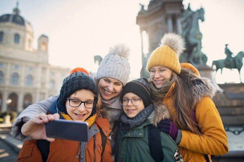A group of people taking a selfie in front of a historical building with statues. 4