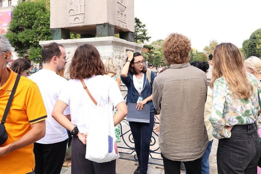 A group of people standing around a stone monument with inscriptions. 4