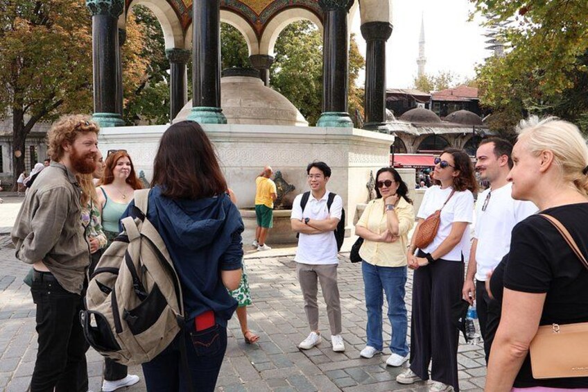 A group of people standing in a public square with a historical monument in the background. 3