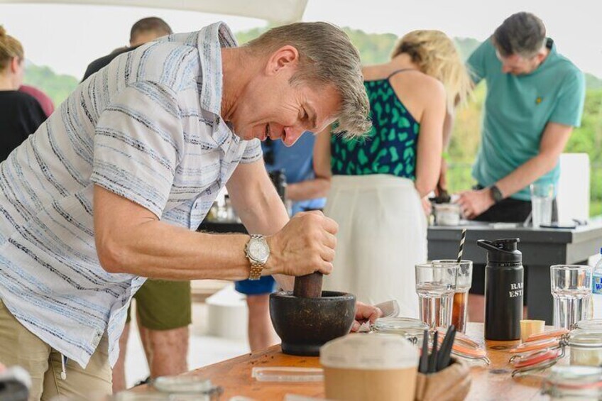 A man preparing a drink at a table with glasses and a coffee pot. 5