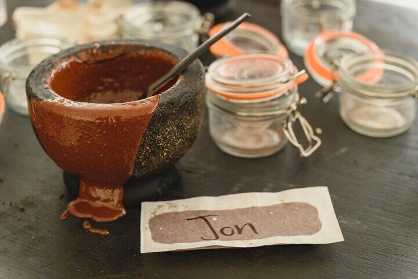A mortar with a pestle, a name tag, and several small glass jars with orange lids. 4