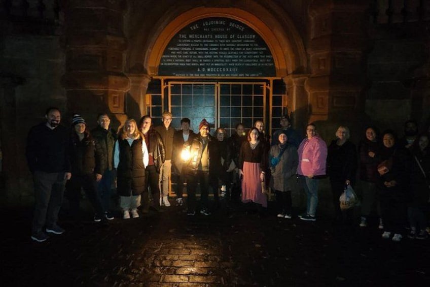 A group of people standing in front of a historic building with a plaque. 2